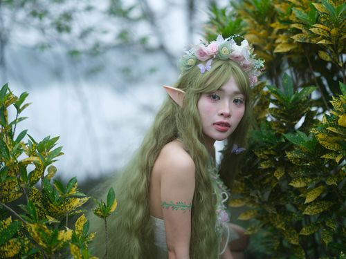 Free A captivating elf woman adorned with floral crown in lush greenery, evoking fantasy. Stock Photo