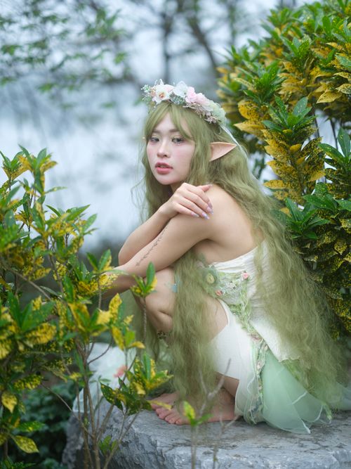 Free Beautiful fantasy portrait of a green-clad elf amidst vibrant foliage. Stock Photo