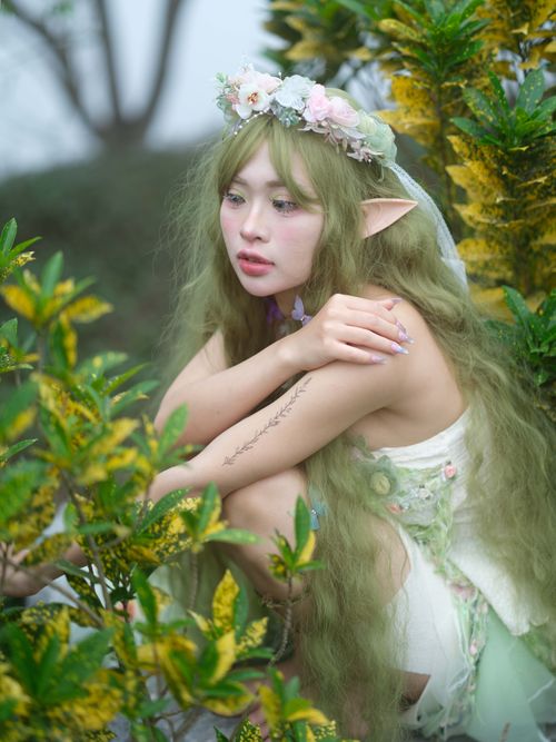 Free Fantasy-themed portrait of an elf woman amidst lush greenery and colorful flora. Stock Photo