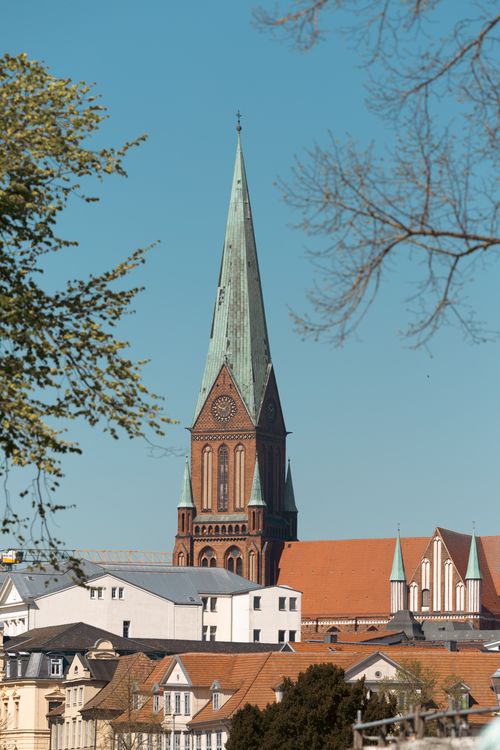Free A scenic view of a historic cathedral tower in Schwerin, Germany, against a clear blue sky. Stock Photo