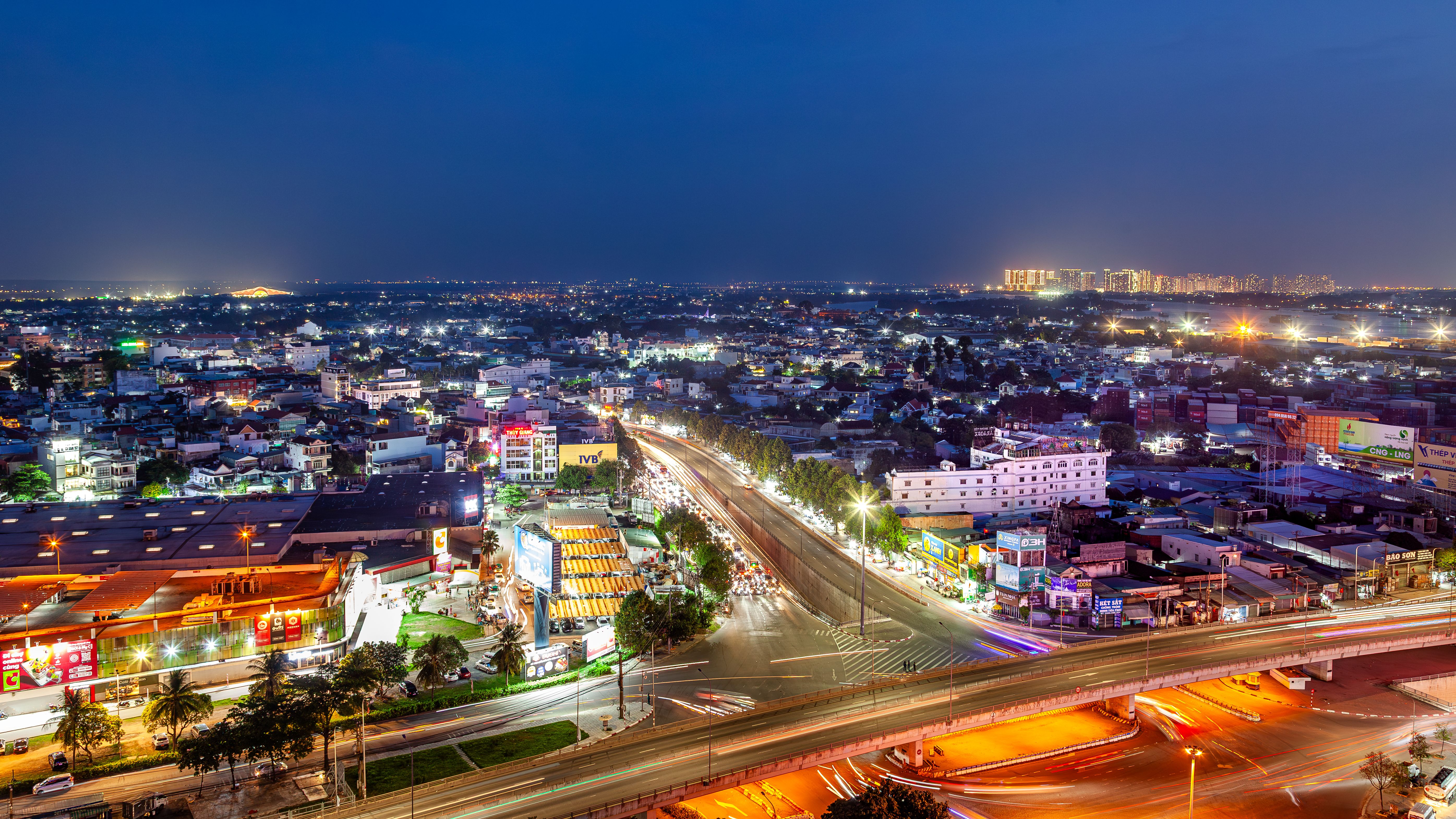 Aerial night view of a vibrant city with illuminated buildings and streets, showcasing urban life from above.