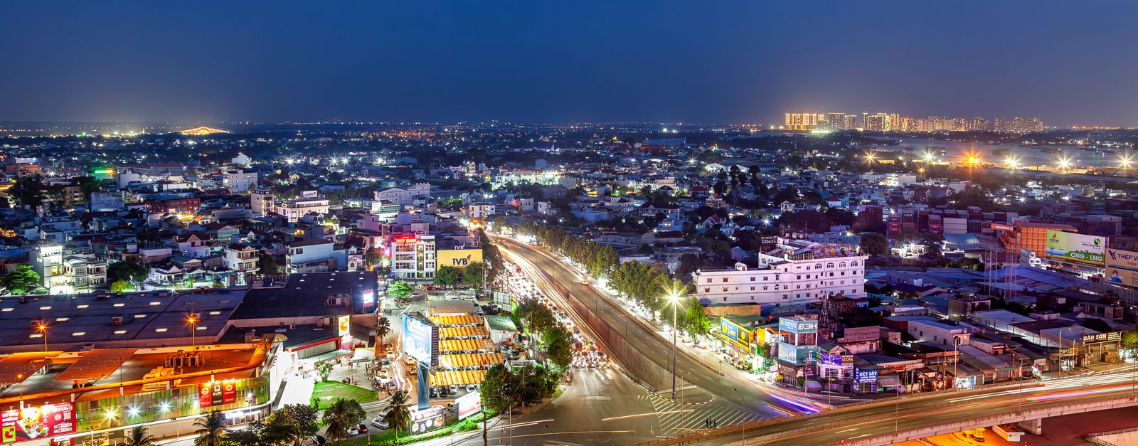 Aerial night view of a vibrant city with illuminated buildings and streets, showcasing urban life from above.