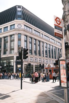 Crowded London street with classic architecture and famous Underground sign.