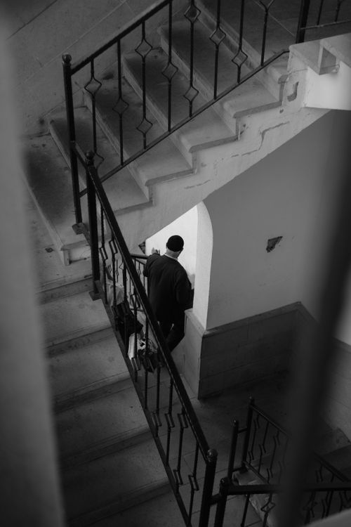 Free A lone figure descends a staircase in a moody black and white setting. Stock Photo