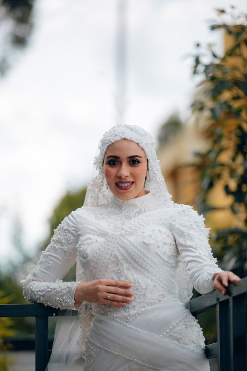 Free Stunning bride wearing a detailed white dress with intricate beading, posing outdoors. Stock Photo