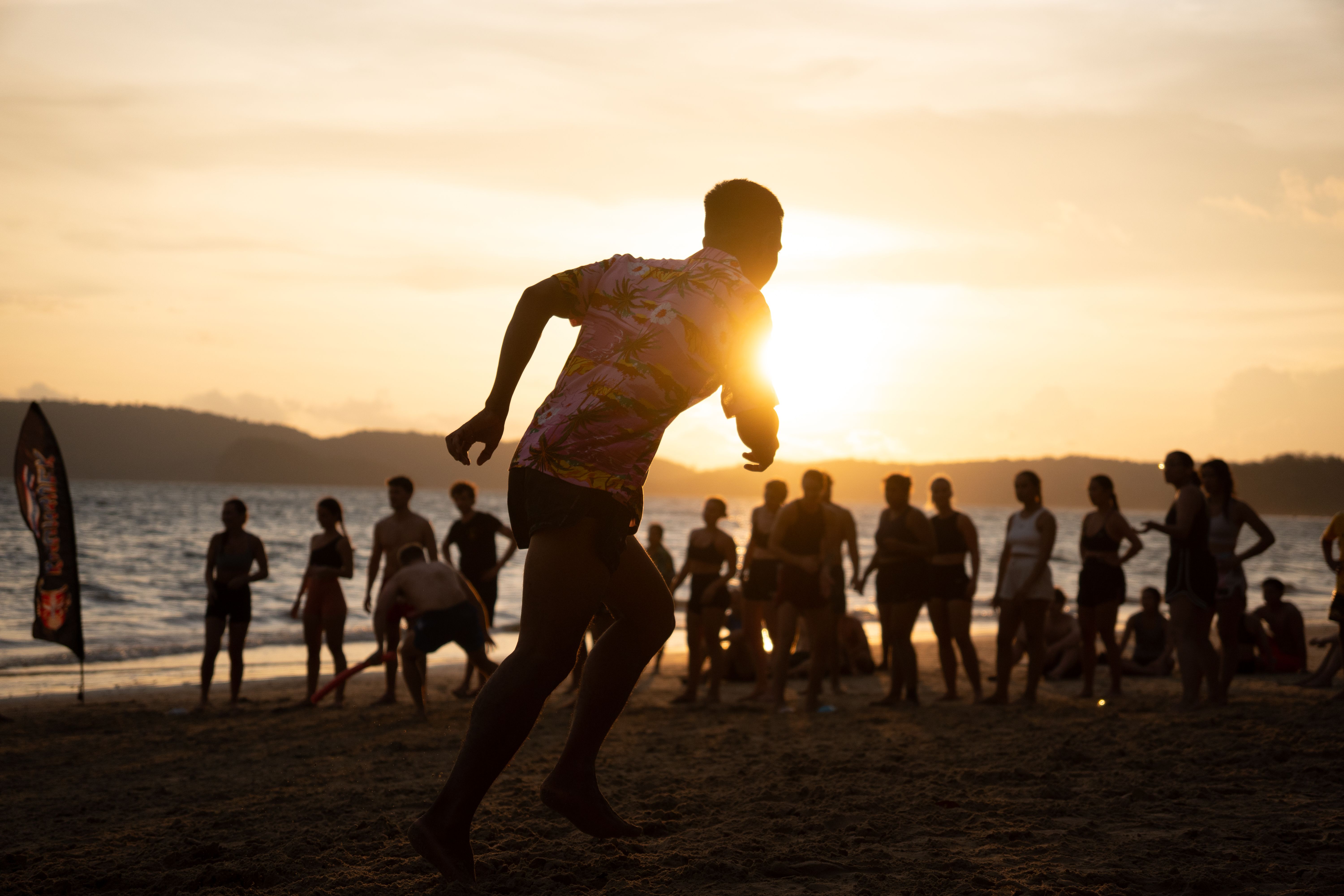 People enjoying beach activities during a tropical sunset at Ao Nang, Krabi, Thailand.