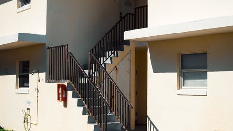A contemporary apartment building exterior featuring a stairway under bright sunlight.