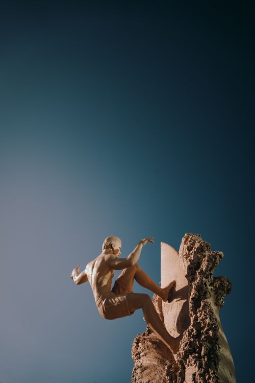 Free A man skillfully climbs a rocky cliff against a clear blue sky, capturing the essence of outdoor adventure. Stock Photo