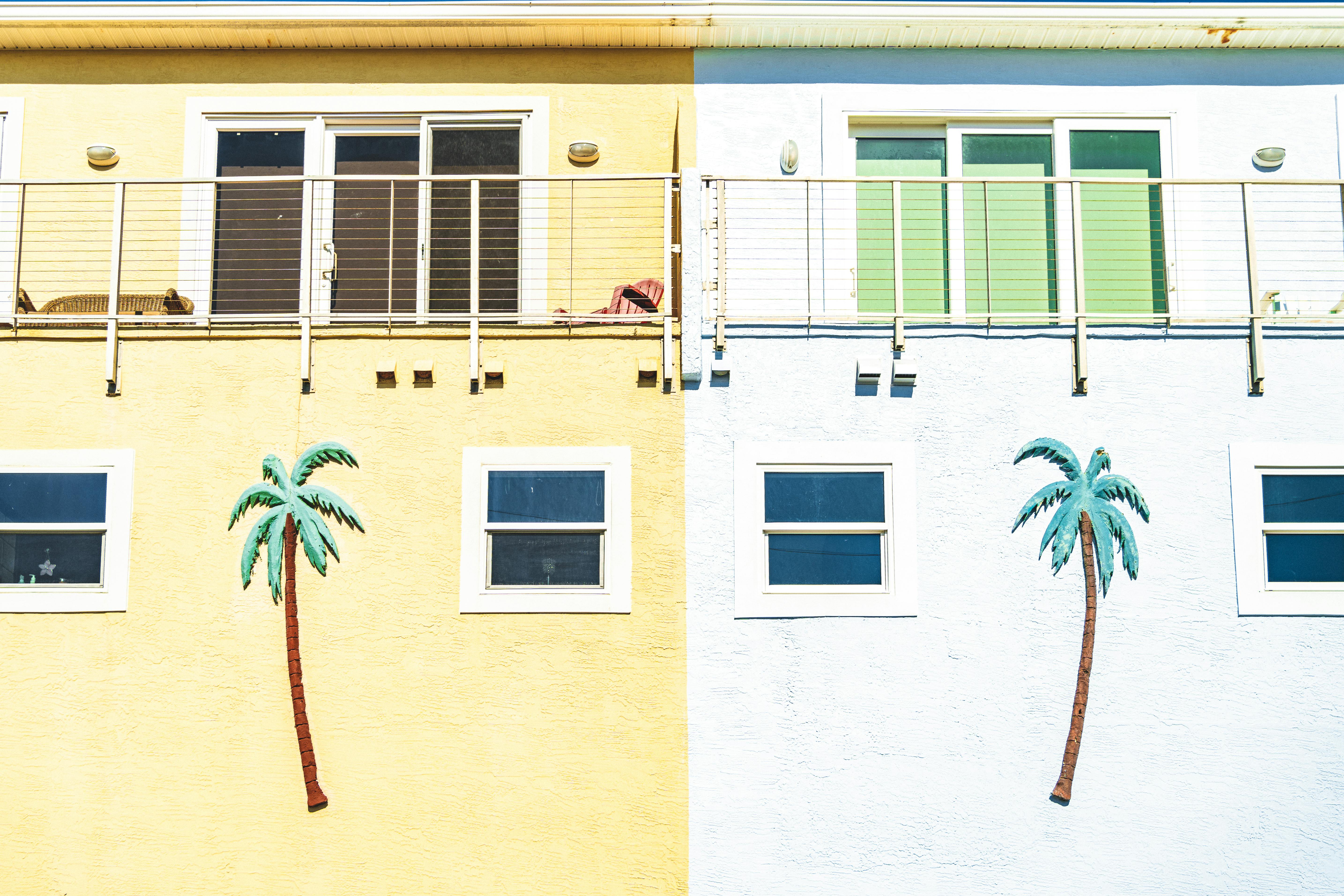 Colorful beachfront building wall featuring decorative palm trees and vibrant tones.