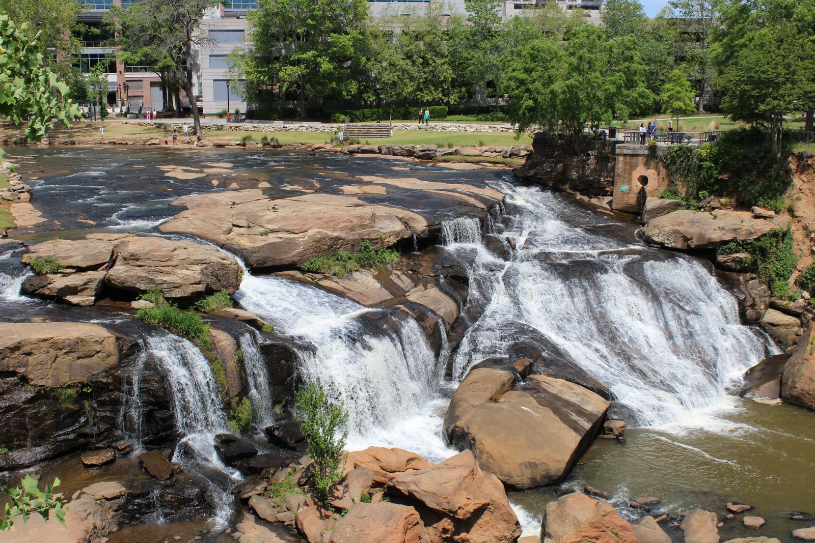Waterfall and pedestrian bridge in Greenville, South Carolina, used as a visual reminder to compare beauty with practical retirement costs.