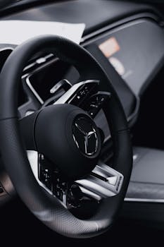 Close-up of a Mercedes-Benz steering wheel inside a luxury car, showcasing sleek design and modern details.