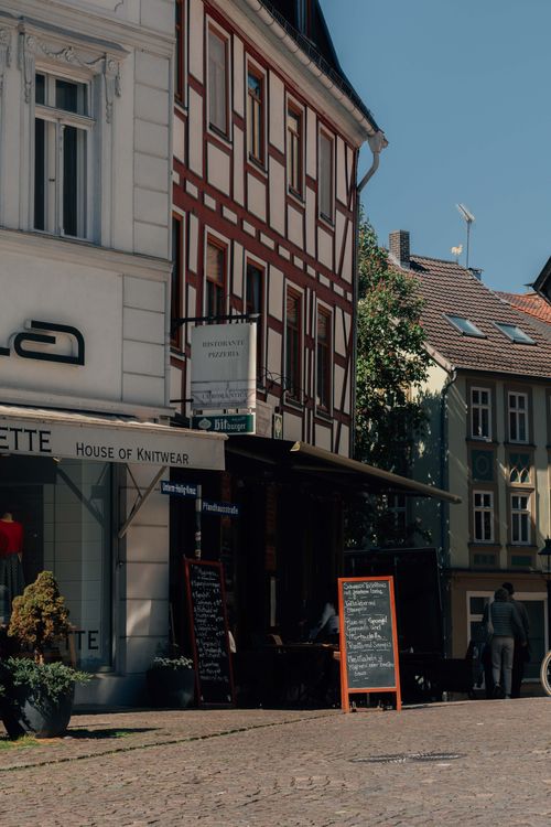 Free Sunny day in a traditional European town with an outdoor café and historic architecture. Stock Photo