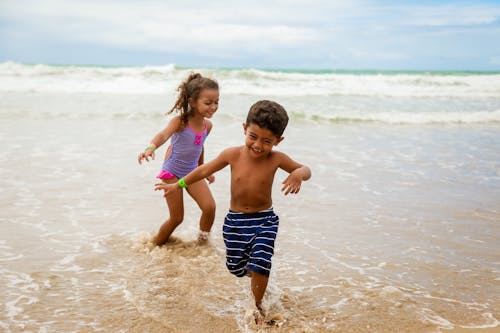 Photo of Children Smiling While Running on Seashore