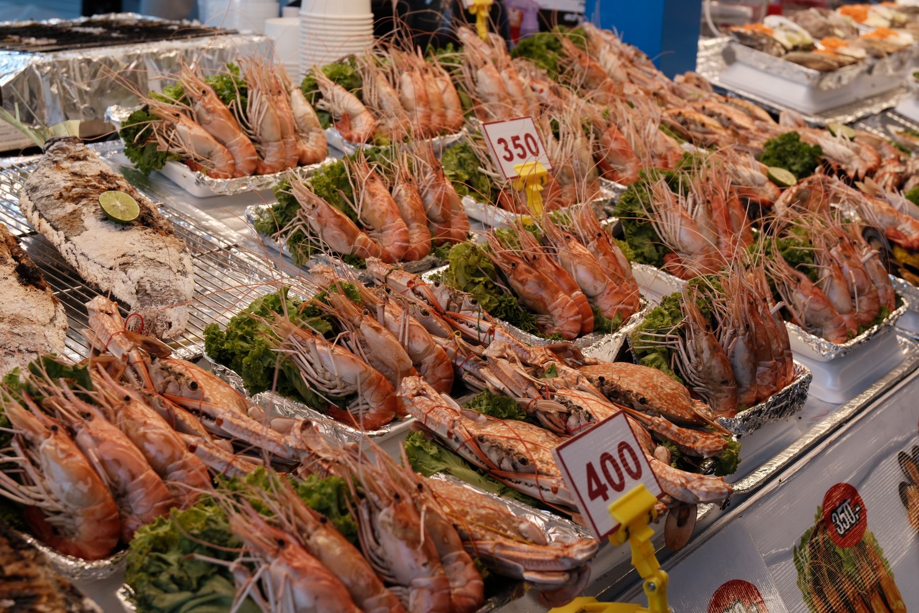 Fresh seafood market display featuring grilled prawns and fish with price tags, ideal for culinary exploration.