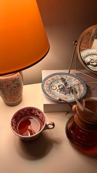 A warm, inviting tea scene with a vintage lamp, mirror, and intricate cups.