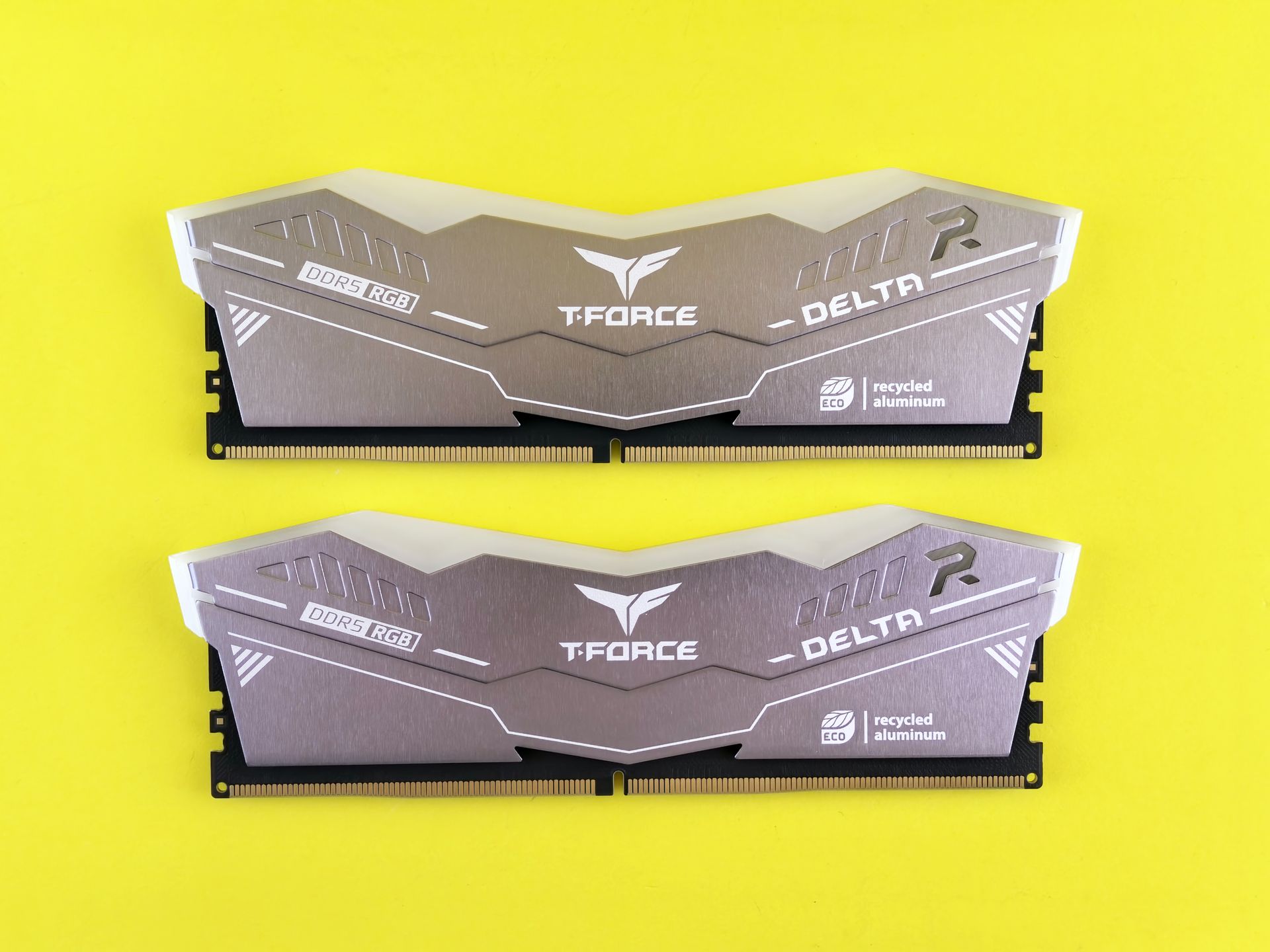 Close-up of two T-Force Delta DDR5 RGB memory sticks on a vibrant yellow background.