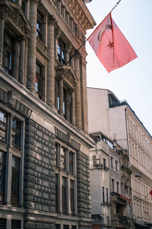 Free View of a historic building in Istanbul featuring a prominent Turkish flag under clear skies. Stock Photo