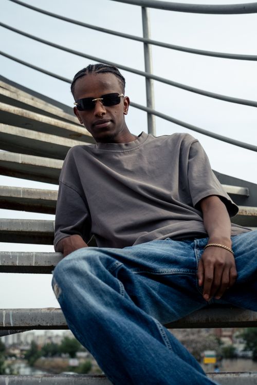 Free Stylish young adult posing outdoors on a metal staircase in a relaxed urban setting. Stock Photo