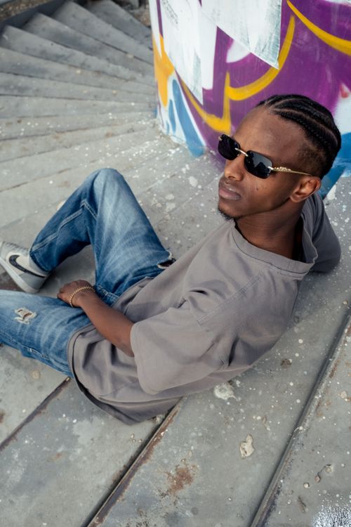 Free Young man in casual attire sits on graffiti-covered steps, showcasing urban street style. Stock Photo