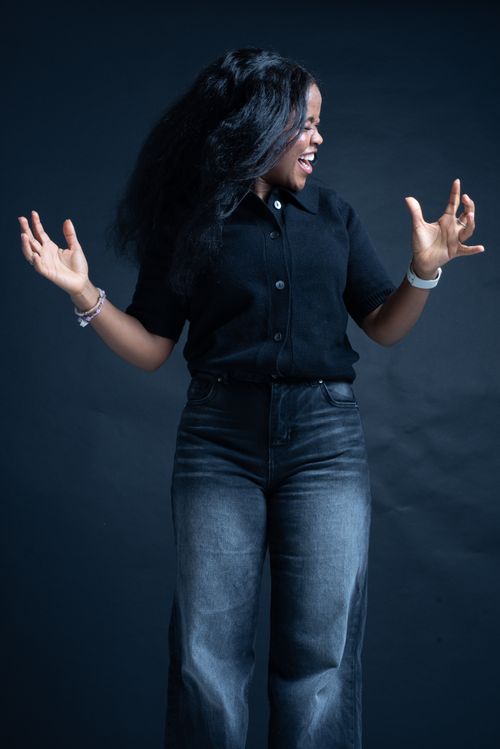 Free Cheerful young woman in casual outfit expressing joy and excitement against dark background. Stock Photo