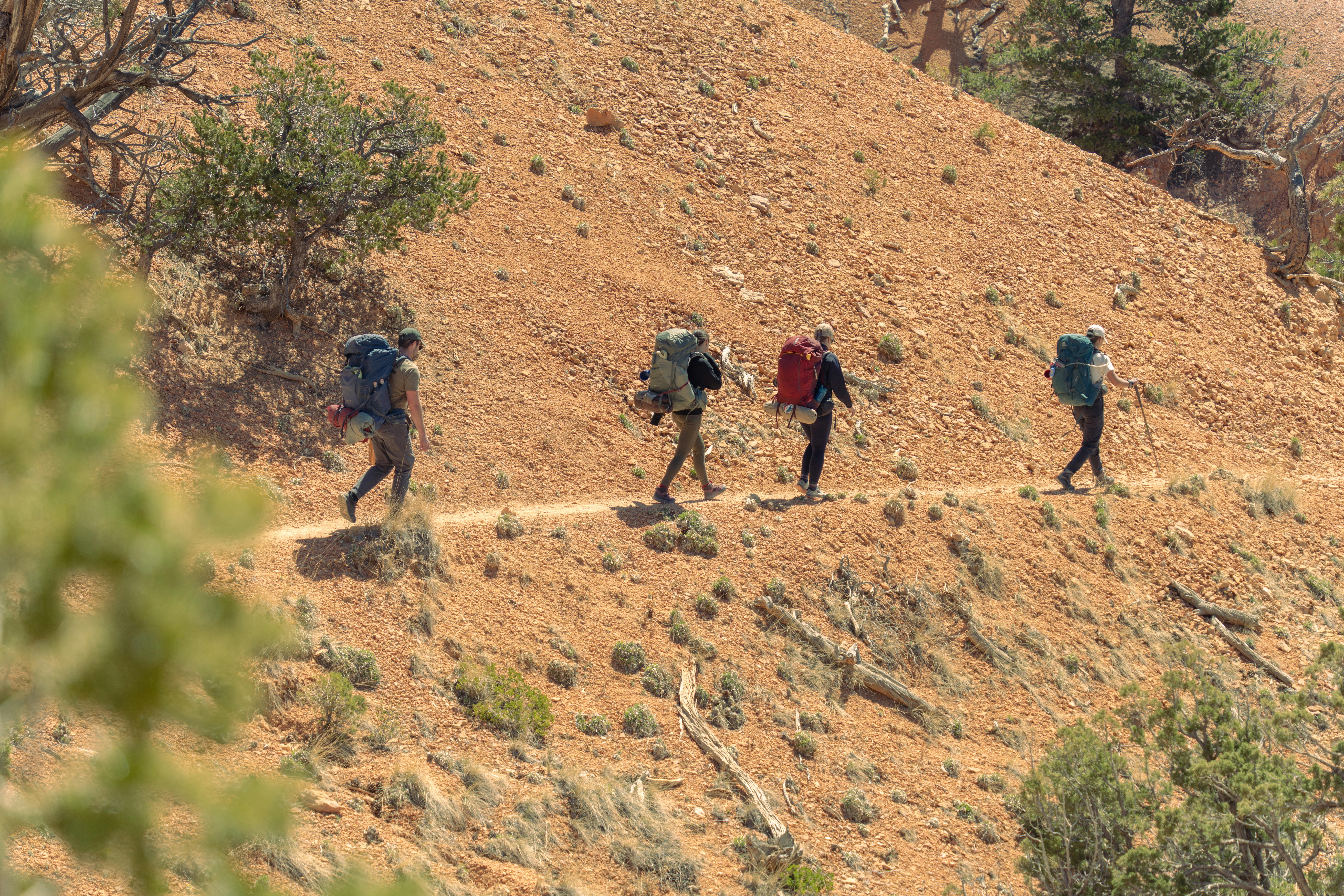 Group of hikers with backpacks navigating the rugged desert landscape of Bryce Canyon, Utah.