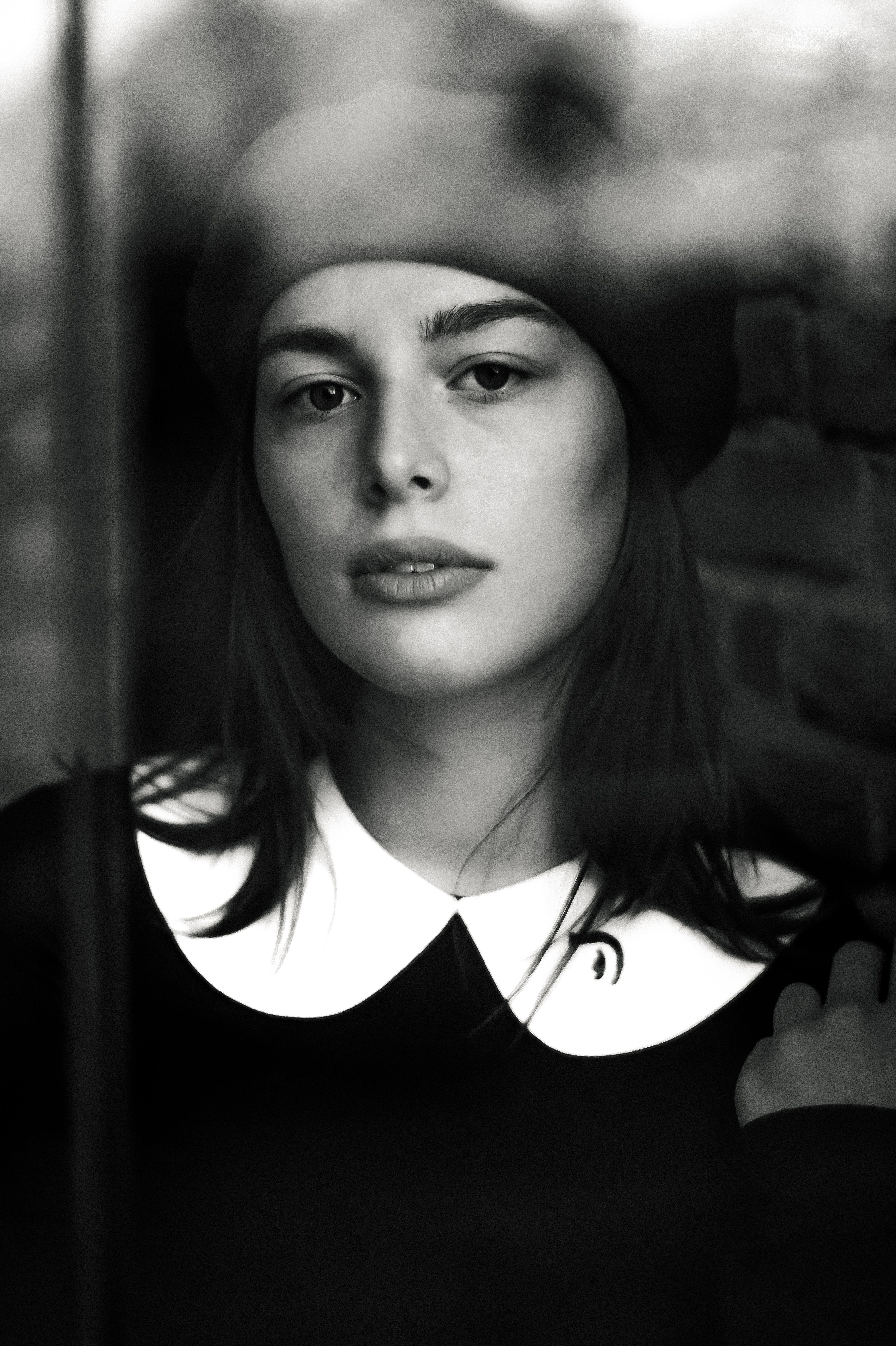 Moody black and white portrait of a woman wearing a beret, showcasing natural beauty and classic style.
