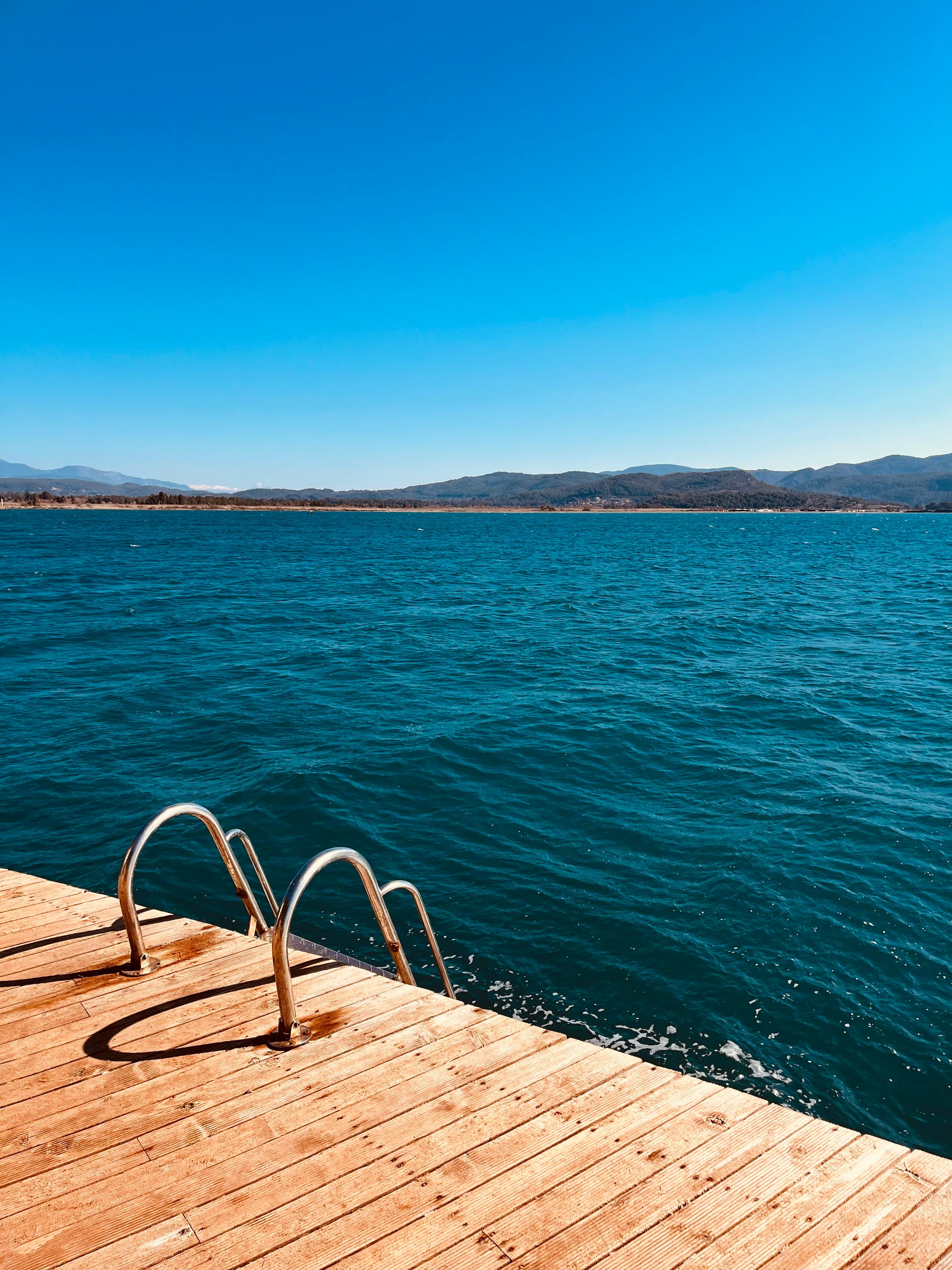 A tranquil view from a wooden pier in Muğla, Türkiye, overlooking sparkling blue waters under a clear sky.