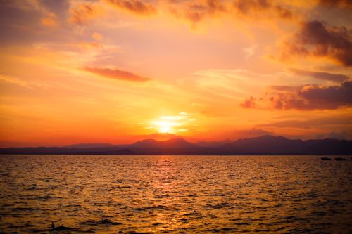Free A breathtaking view of the sun setting over the ocean, casting vibrant colors across the sky. Stock Photo
