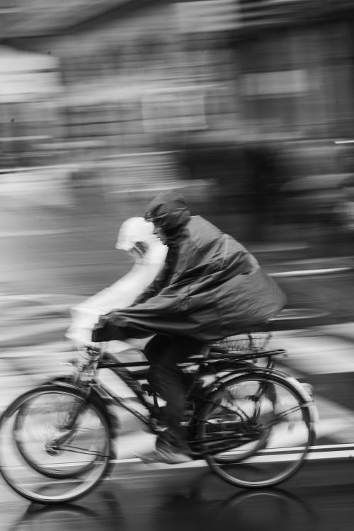 Free Cyclists riding through Cologne's streets in heavy rain, captured with motion blur. Stock Photo