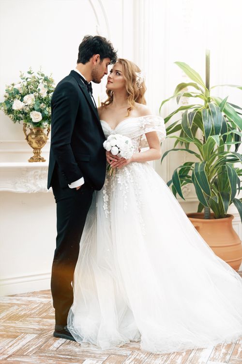 Free A romantic wedding photo of a bride and groom indoors, embracing in classic attire. Stock Photo