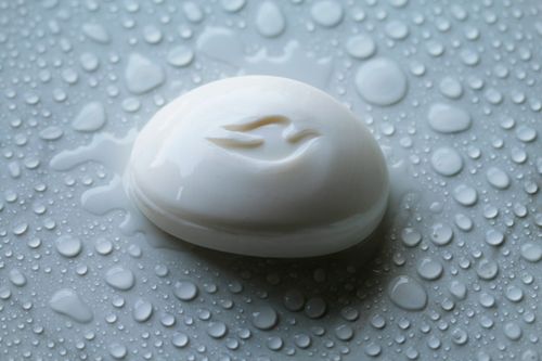 Free Close-up of a white soap bar surrounded by water droplets on a flat surface. Stock Photo