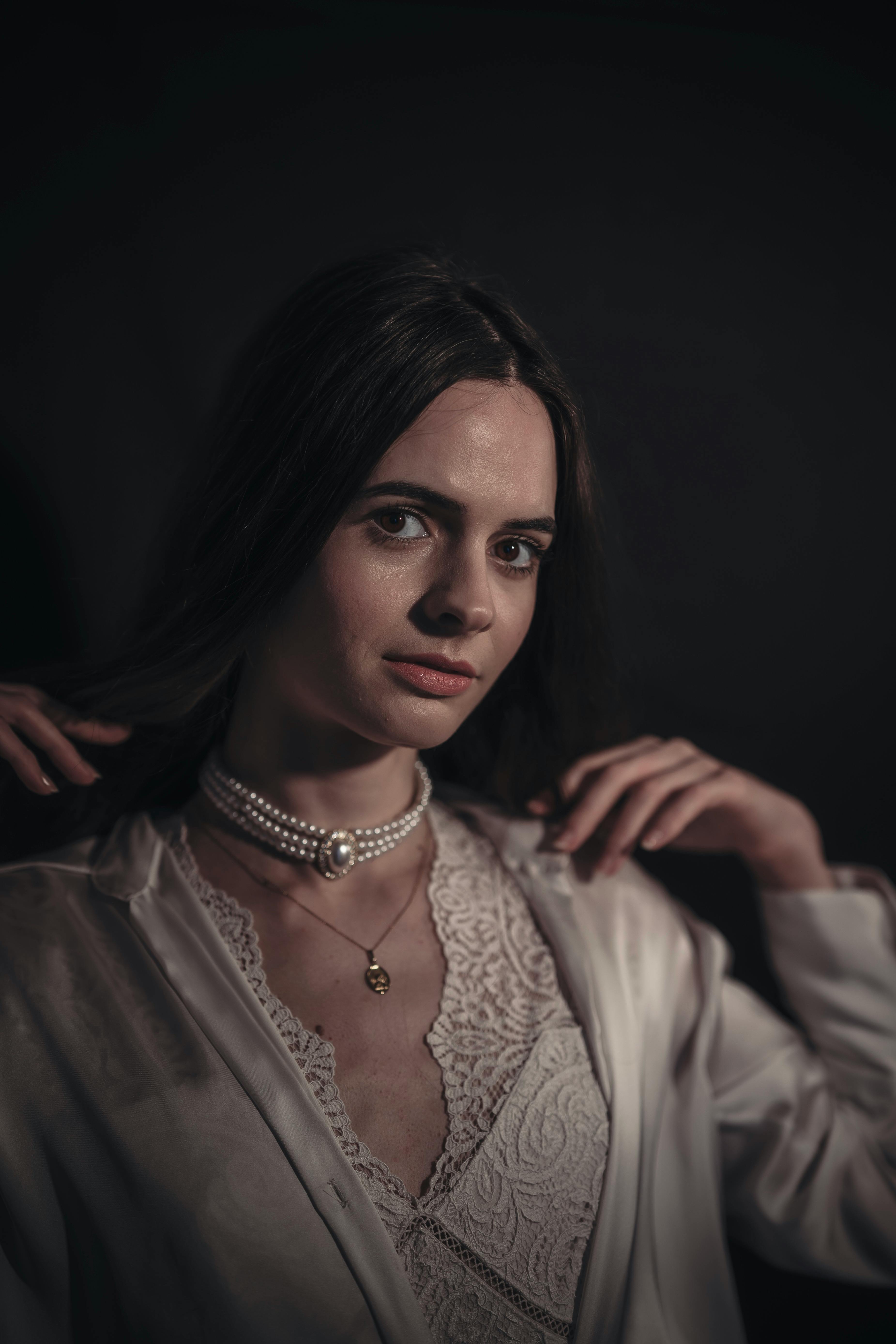 Portrait of a woman in elegant attire showcasing pearls under soft lighting.