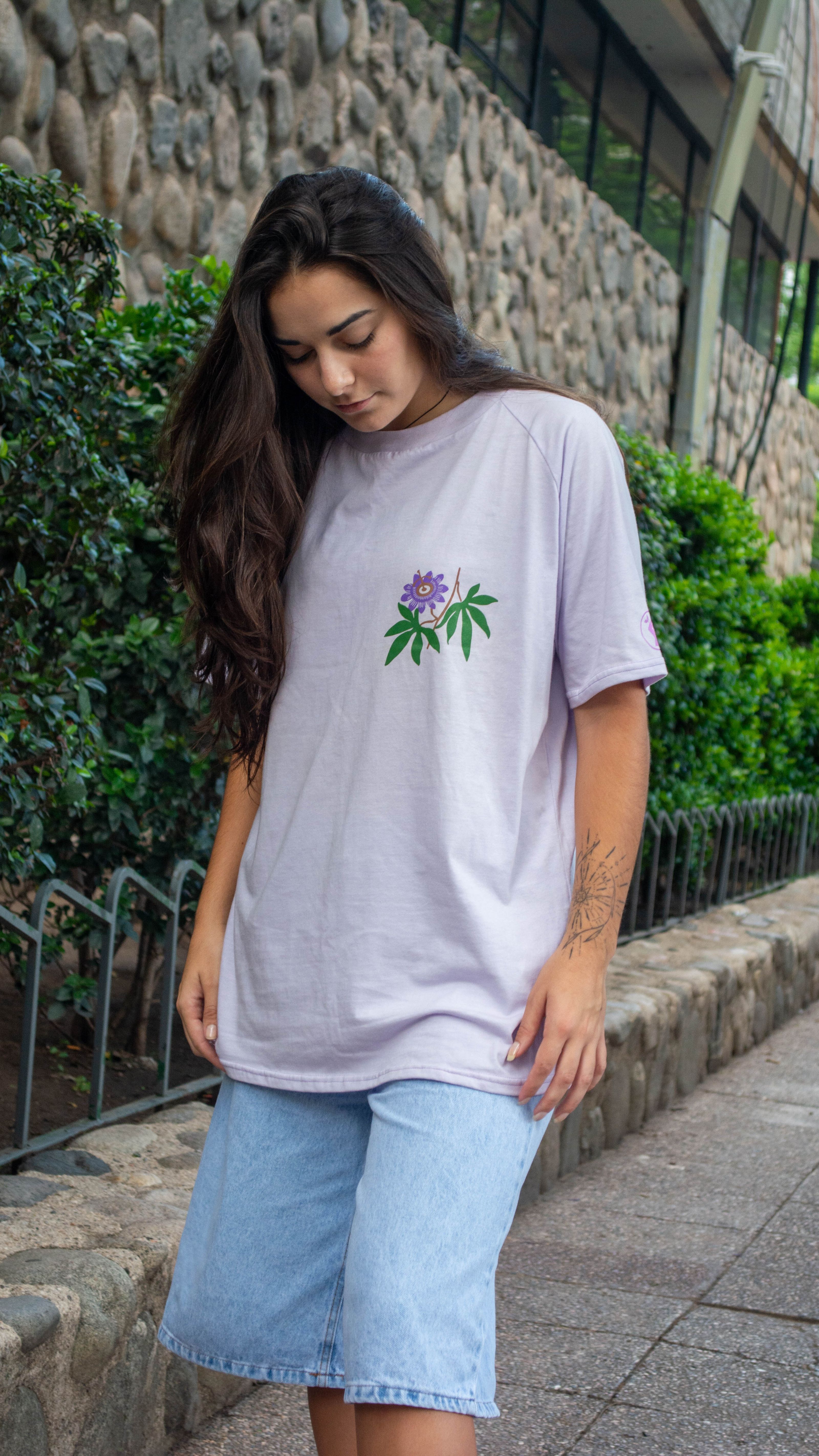 Jovem mulher com camiseta florida posa ao ar livre exibindo estilo casual de rua.
