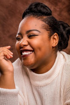 工作室环境中，一位发型优雅的非裔美国女性微笑着，特写镜头捕捉了她快乐的神情