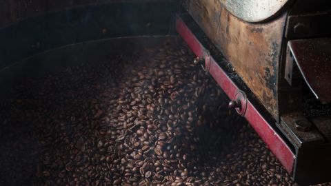 Close-up of coffee beans being roasted in an industrial machine, highlighting the roasting process.
