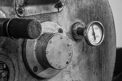 A detailed black and white image of an industrial coffee roaster machine, highlighting gauge and metal textures.