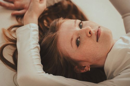 Free A serene portrait of a woman with red hair lying and looking up calmly. Stock Photo