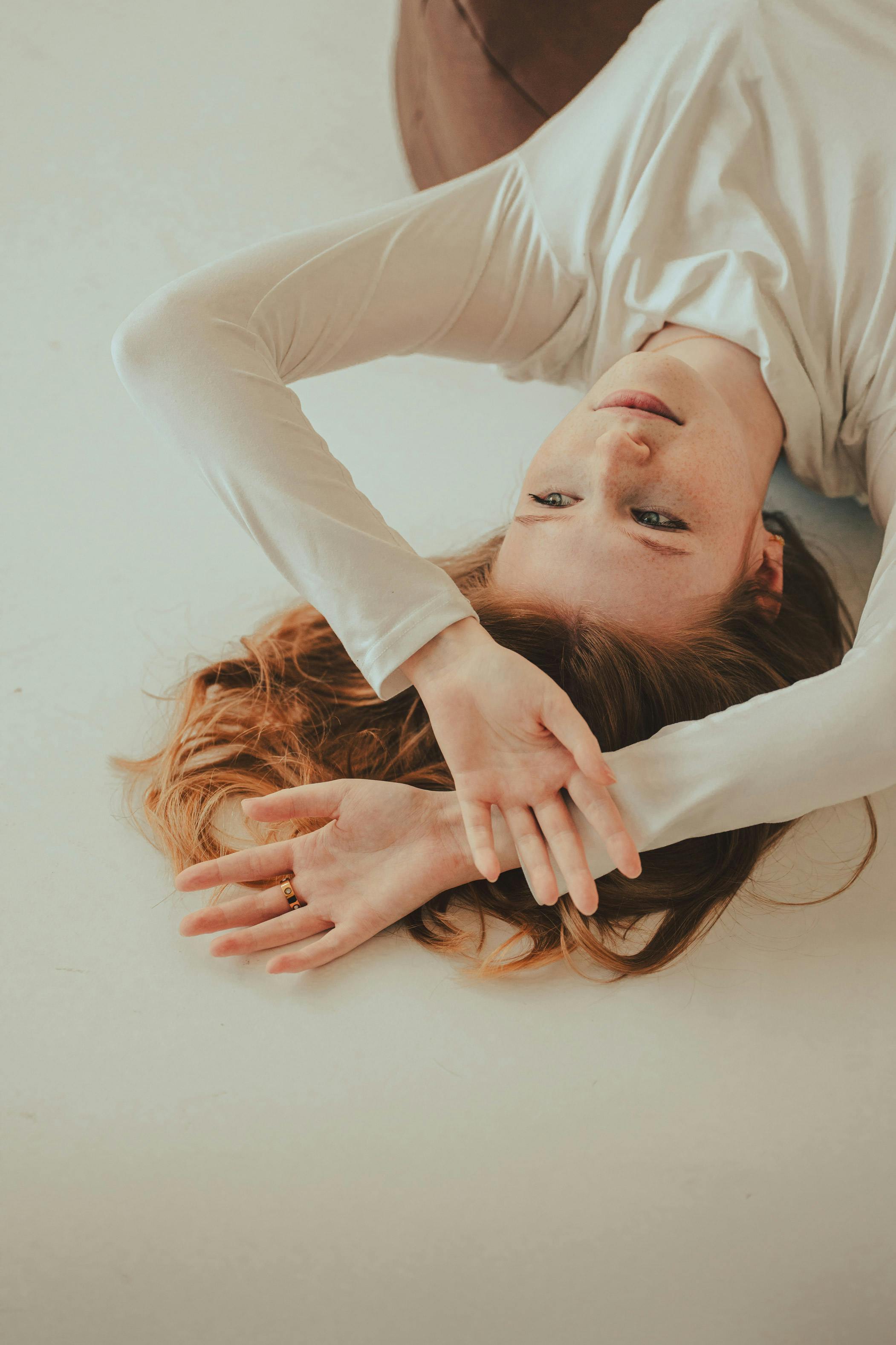 Serene woman lying on a white surface, enjoying a moment of relaxation indoors in Bremen, Germany.