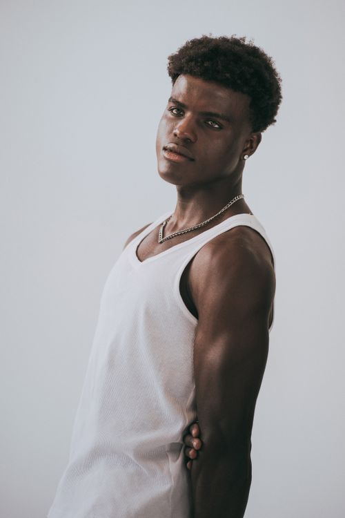 Free Stylish portrait of a young man in a white tank top exuding confidence and poise. Stock Photo