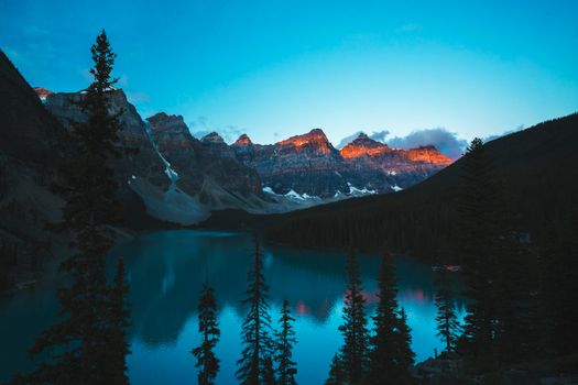 Peaceful sunrise view over Moraine Lake with mountain peaks in Banff National Park.