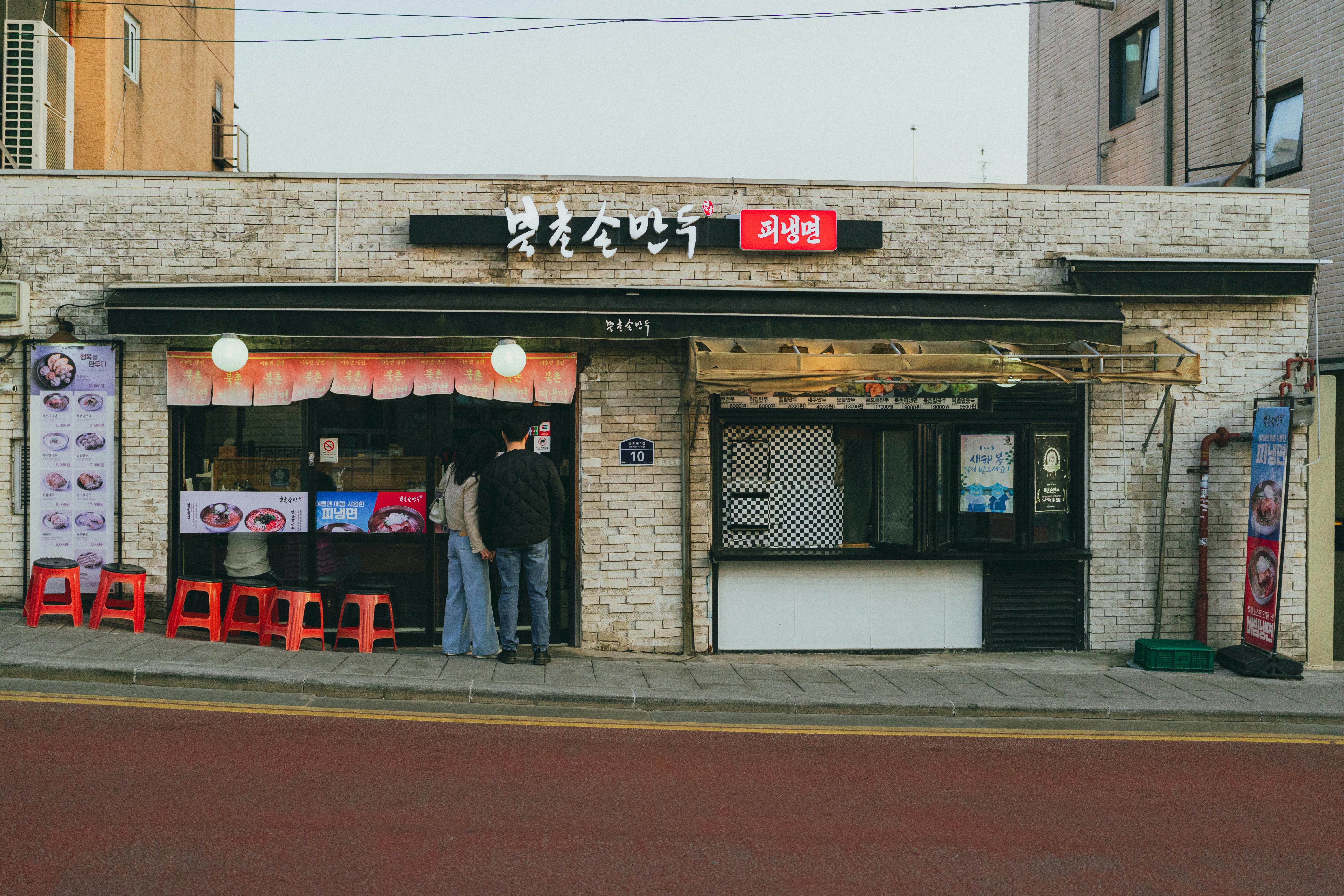 Street view of a Korean eatery with a rustic facade in Seoul, capturing local life.