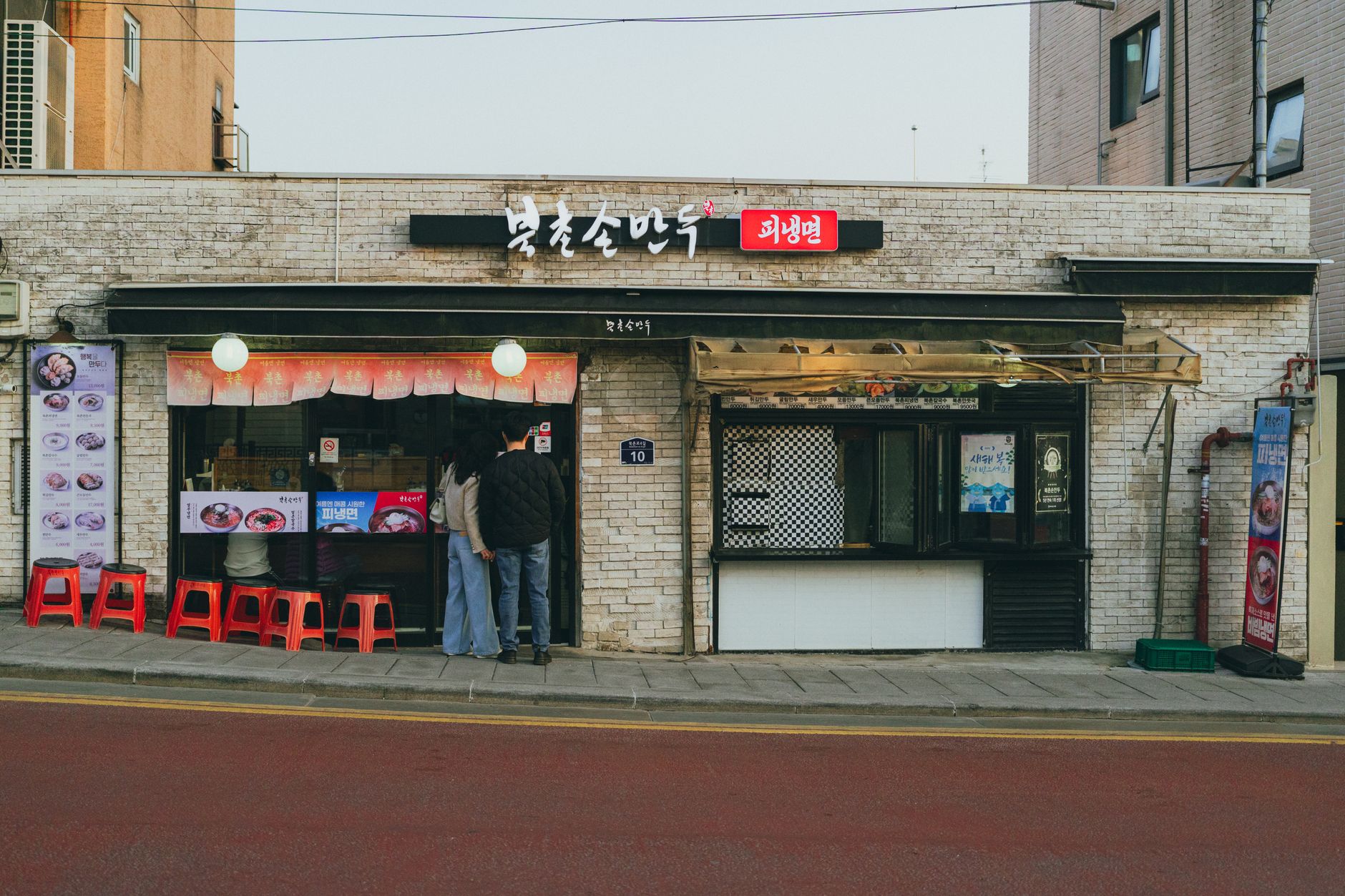 Street view of a Korean eatery with a rustic facade in Seoul, capturing local life.