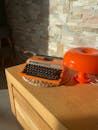 Vintage Orange Typewriter and Retro Lamp on Wooden Desk