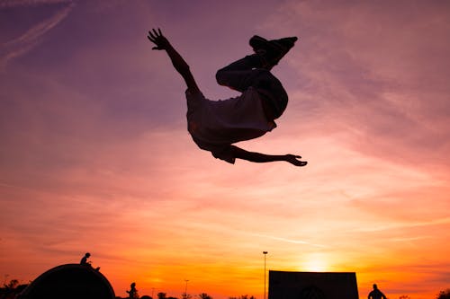 Person in White Shirt Jumping during Sunset