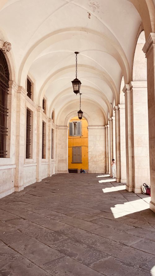 Free A beautiful colonnade with arched ceilings and classical architecture illuminated by sunlight. Stock Photo