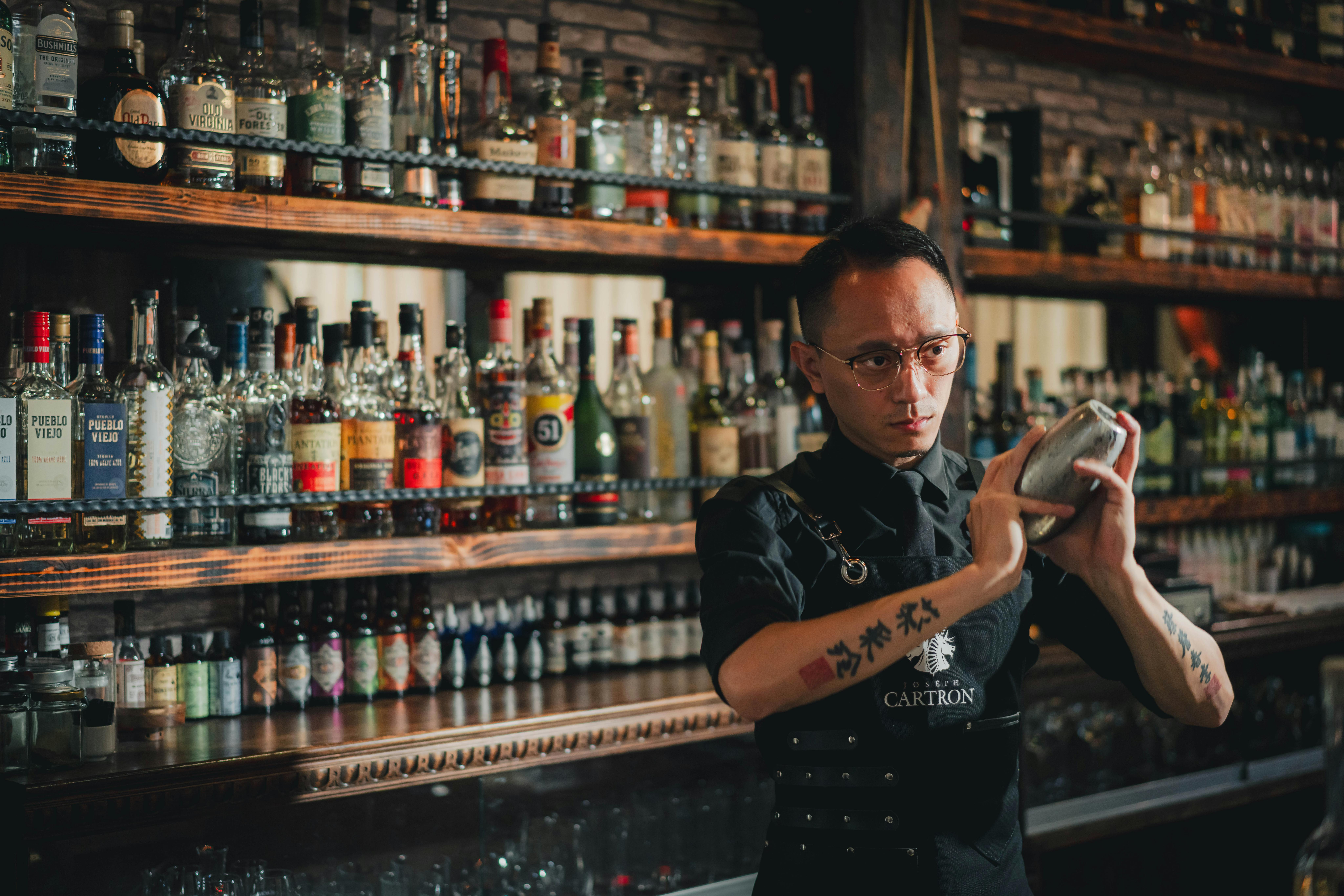 Kostnadsfria En mixolog skakar cocktails på en elegant bar i Taiwan och visar upp expertkunskaper och ett pulserande utbud av spritsorter. Stock foto