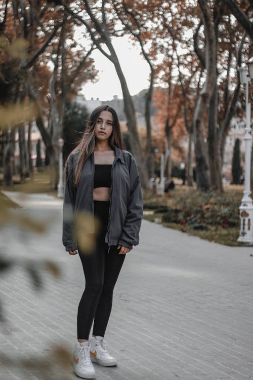 公園を歩いている灰色のジャケットの女性の浅い焦点の写真