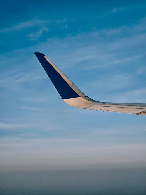 Free View of an airplane wing soaring above clouds with a clear blue sky. Stock Photo