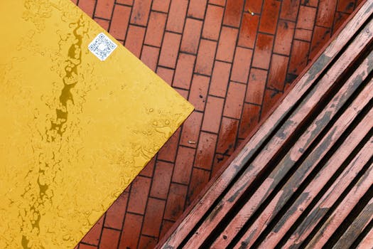 Top view of a rain-soaked bench and yellow table with urban brick pattern.