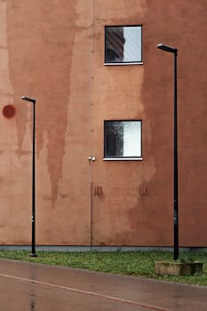 Modern urban scene with two street lamps and a textured building wall.